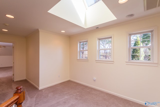 carpeted spare room with ornamental molding and a skylight