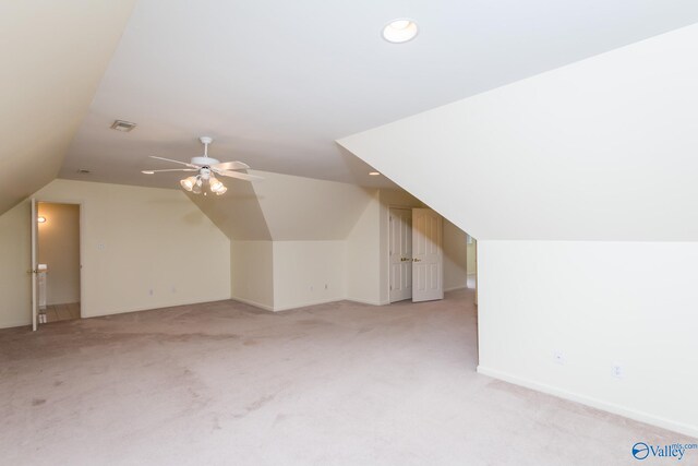 additional living space with ceiling fan, light colored carpet, and vaulted ceiling