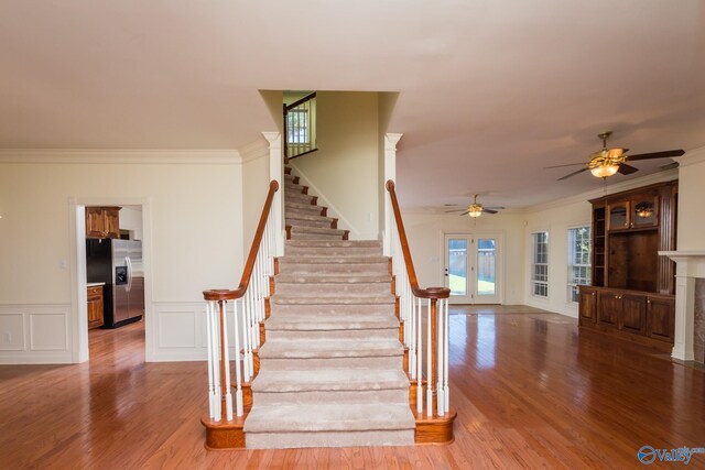 stairs with a tiled fireplace, ornamental molding, and hardwood / wood-style flooring