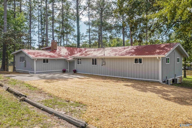 rear view of property with a chimney and metal roof