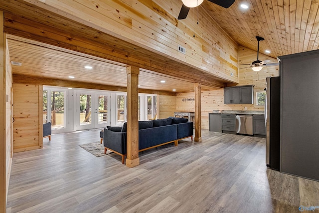living room with a ceiling fan, a healthy amount of sunlight, wood walls, and wood ceiling