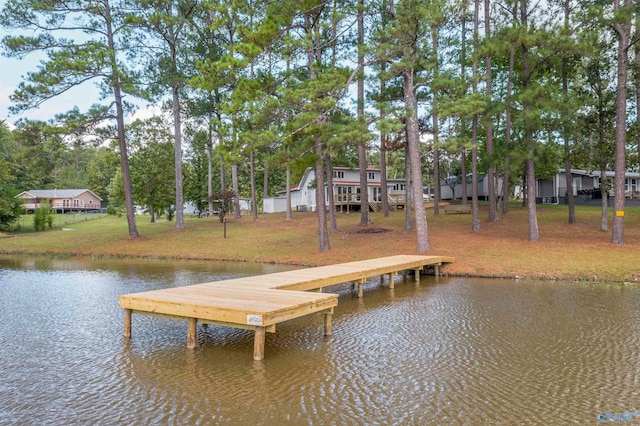 view of dock with a lawn and a water view