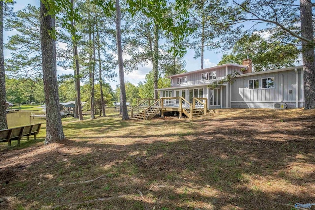 back of house with a sunroom, a wooden deck, stairway, board and batten siding, and a chimney