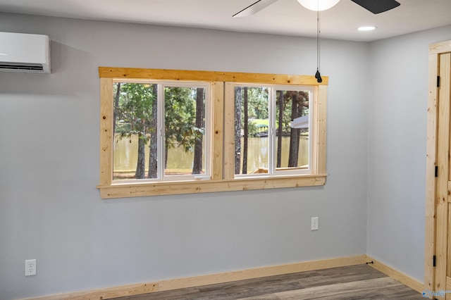 empty room with a wall unit AC, baseboards, recessed lighting, wood finished floors, and a ceiling fan