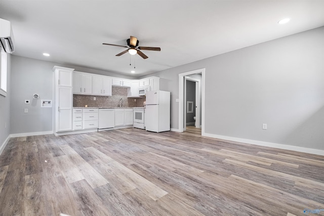 unfurnished living room featuring recessed lighting, a sink, ceiling fan, light wood-style flooring, and baseboards