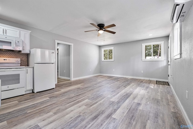 kitchen featuring white cabinets, light wood finished floors, a wall mounted AC, white appliances, and a ceiling fan