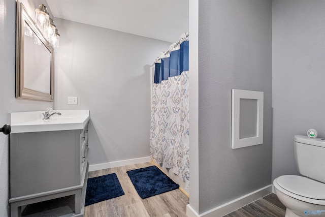 full bath featuring a shower with curtain, vanity, toilet, baseboards, and wood finished floors