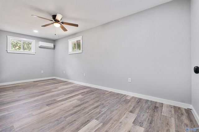 spare room with ceiling fan, a healthy amount of sunlight, a wall mounted AC, and baseboards