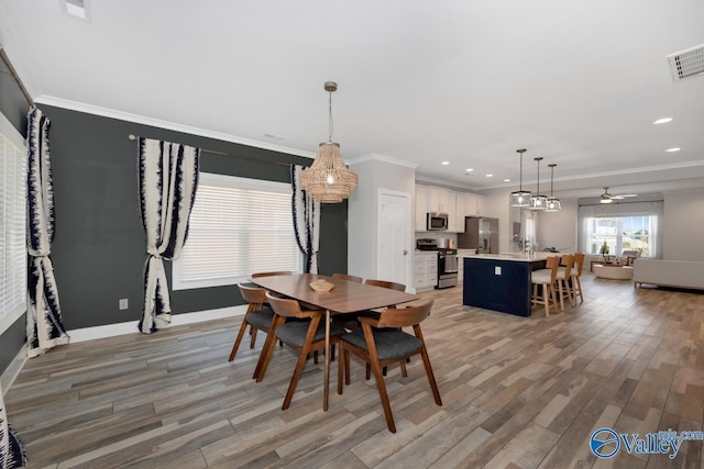 dining space with light wood-style floors, crown molding, and visible vents