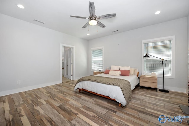 bedroom with wood finished floors, visible vents, and baseboards