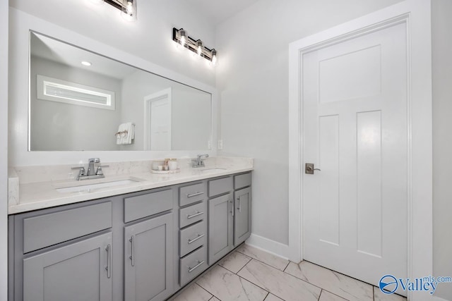 bathroom with double vanity, baseboards, marble finish floor, and a sink