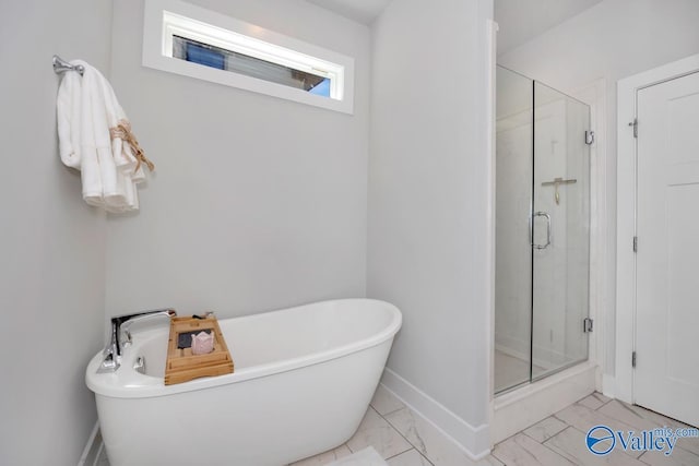 bathroom featuring marble finish floor, a shower stall, and a soaking tub