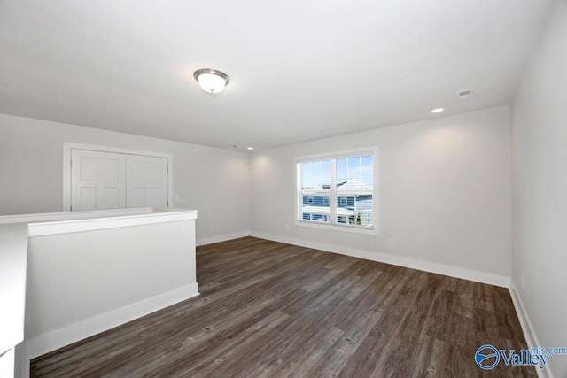 empty room featuring baseboards, visible vents, and dark wood-style flooring