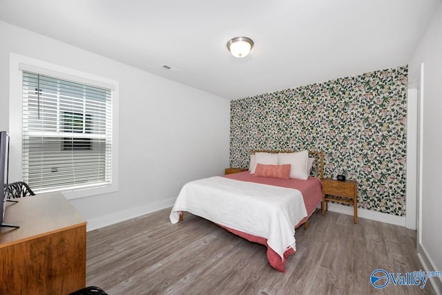 bedroom with visible vents, wallpapered walls, baseboards, and an accent wall
