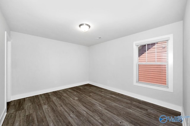 spare room featuring dark wood-style flooring and baseboards