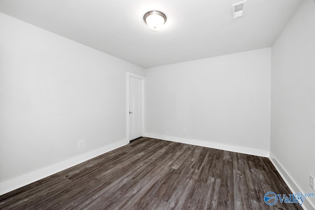 empty room with visible vents, baseboards, and dark wood-type flooring