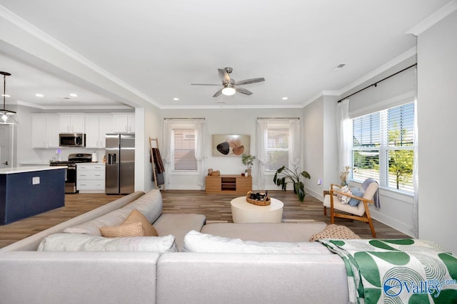 living room with light wood-type flooring, ornamental molding, ceiling fan, and recessed lighting