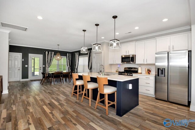 kitchen with dark wood-type flooring, visible vents, light countertops, appliances with stainless steel finishes, and an island with sink