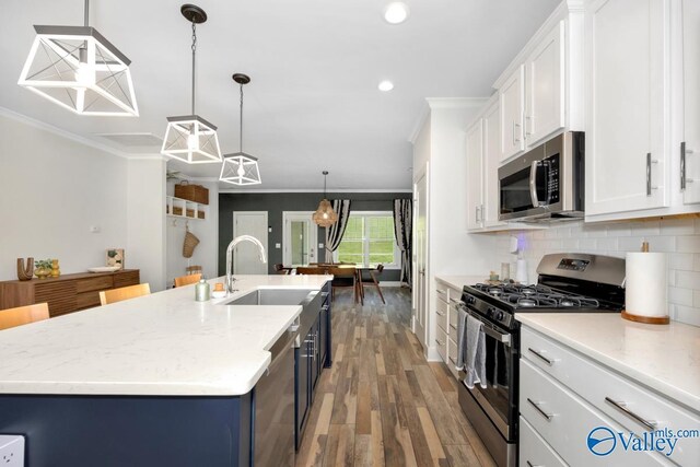 kitchen with recessed lighting, stainless steel appliances, white cabinets, a sink, and crown molding