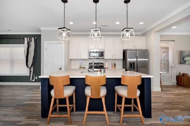 kitchen featuring baseboards, white cabinets, appliances with stainless steel finishes, and a center island with sink