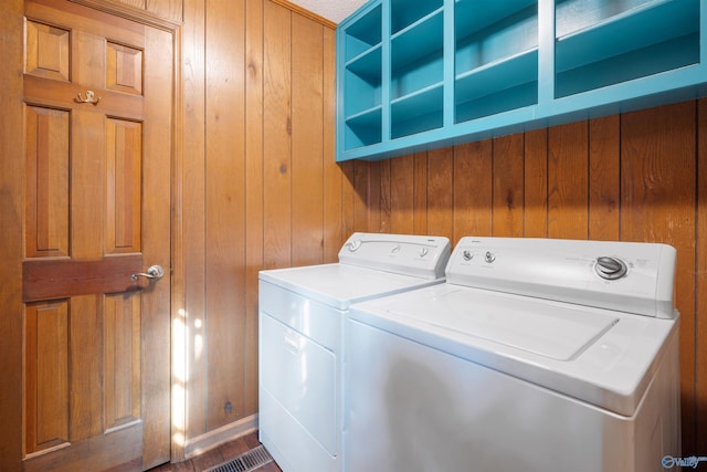 clothes washing area featuring wooden walls and washer and dryer
