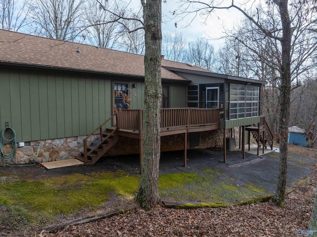 rear view of house featuring a wooden deck, a sunroom, and central AC unit