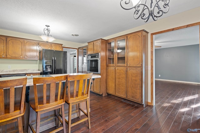 kitchen featuring decorative light fixtures, dark wood-type flooring, black appliances, and a breakfast bar
