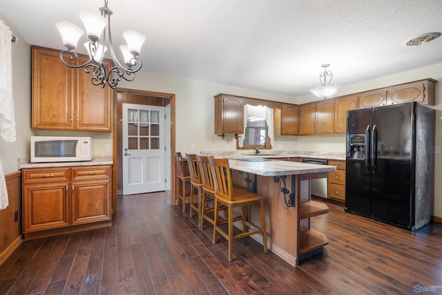 kitchen with black fridge, dark hardwood / wood-style flooring, sink, and hanging light fixtures