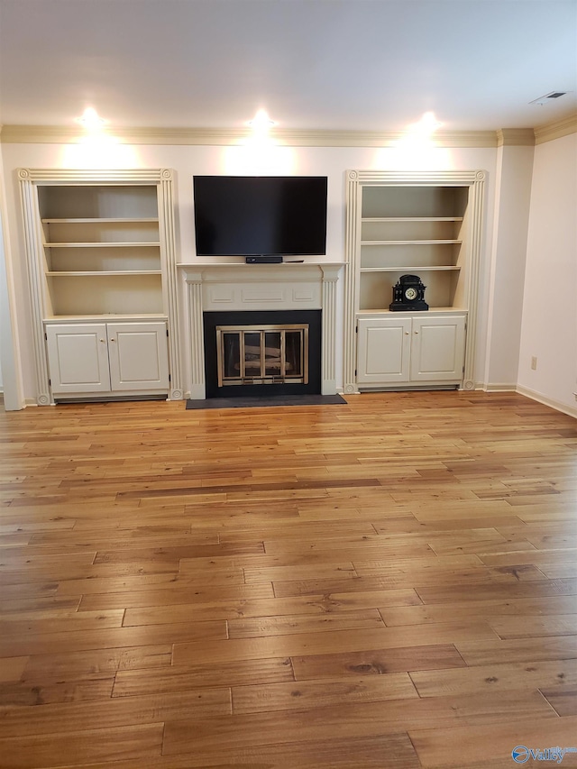 unfurnished living room with built in shelves, light wood-type flooring, and crown molding