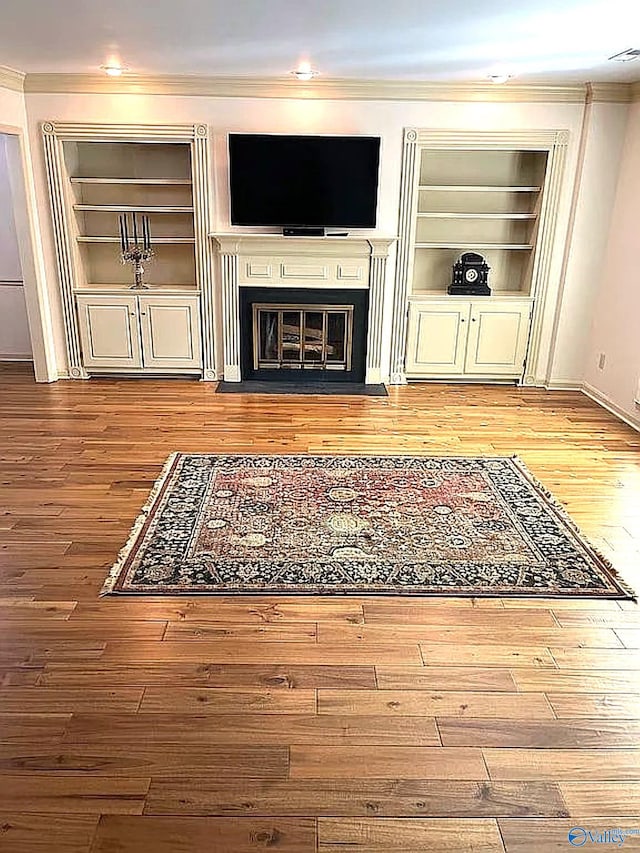 living room with built in shelves, light hardwood / wood-style flooring, and crown molding