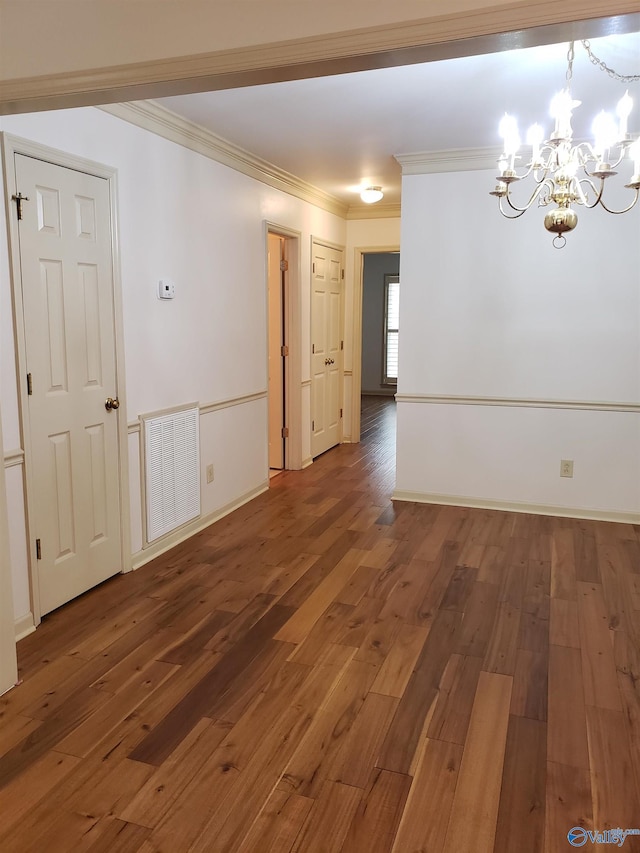 empty room featuring dark hardwood / wood-style flooring, an inviting chandelier, and ornamental molding