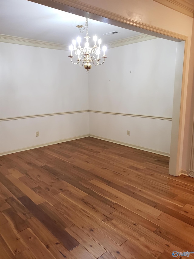 spare room with ornamental molding, hardwood / wood-style flooring, and a notable chandelier