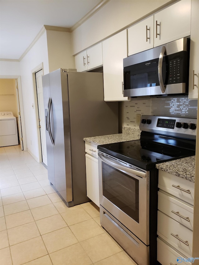 kitchen with light stone countertops, tasteful backsplash, washer / dryer, white cabinets, and appliances with stainless steel finishes