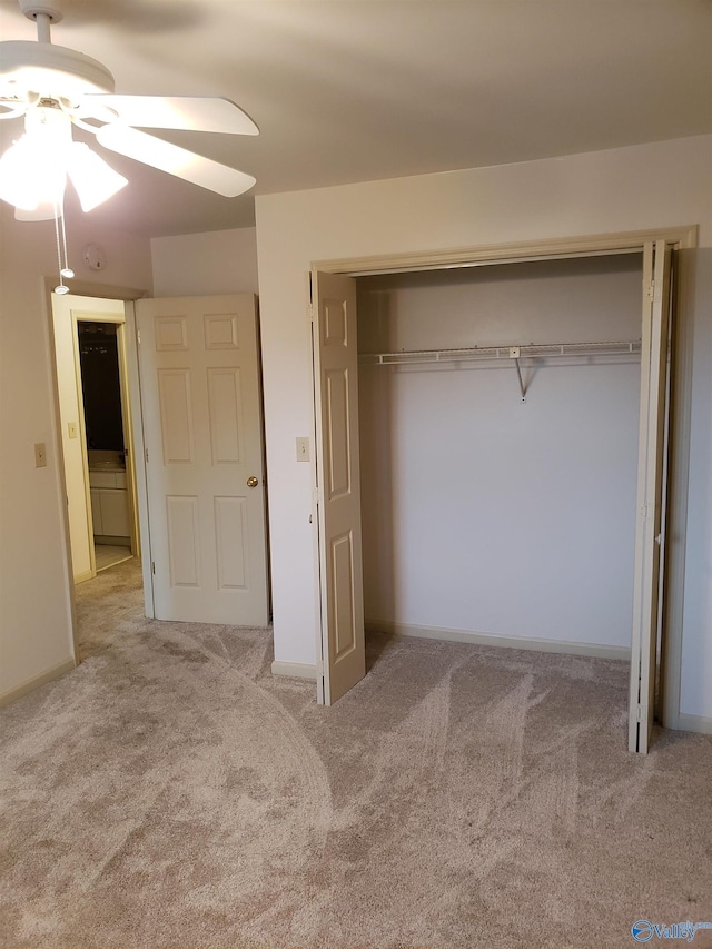 unfurnished bedroom featuring ceiling fan, a closet, and light colored carpet