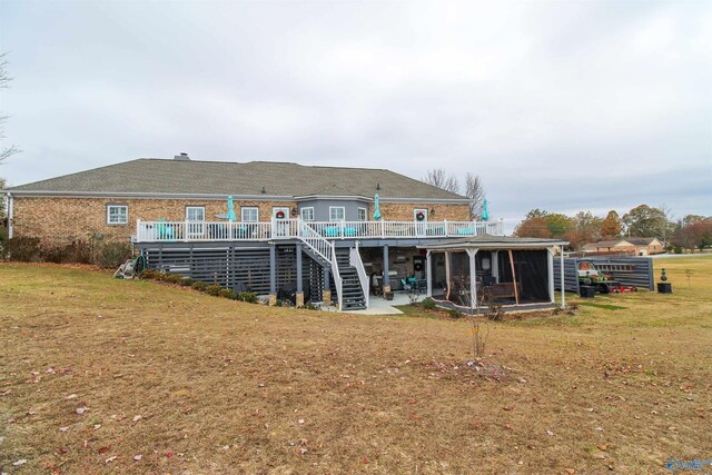 rear view of house with a lawn, a wooden deck, and a patio