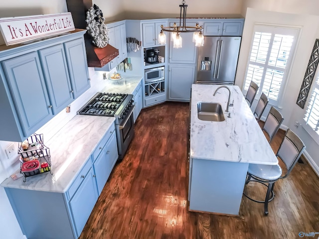 kitchen featuring a kitchen bar, appliances with stainless steel finishes, sink, blue cabinetry, and pendant lighting