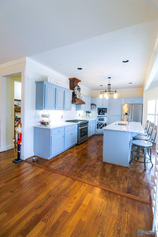 kitchen featuring appliances with stainless steel finishes, a breakfast bar, a kitchen island with sink, pendant lighting, and dark hardwood / wood-style floors