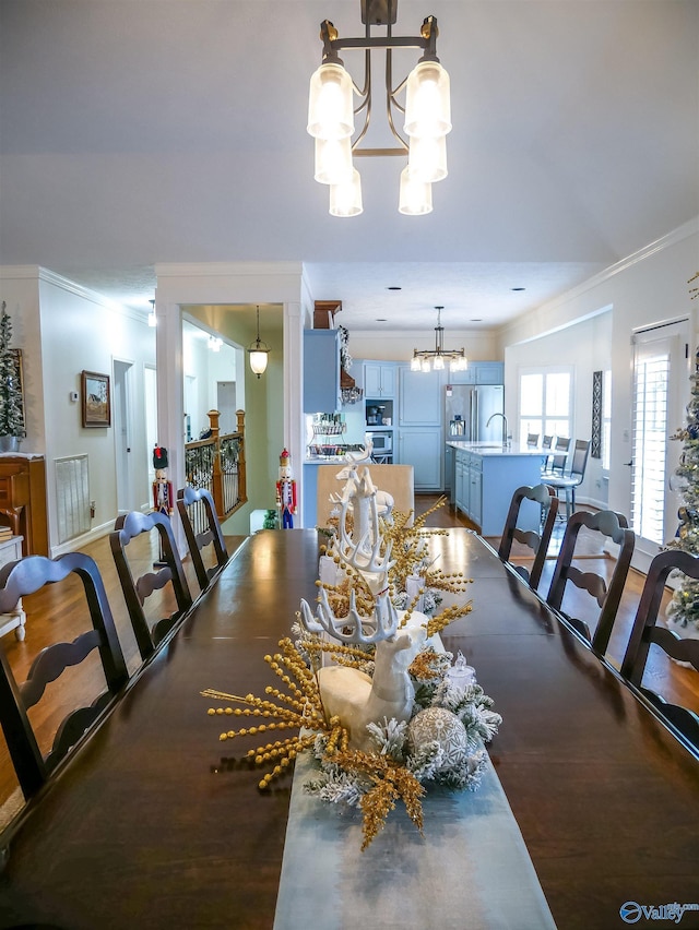 dining area with an inviting chandelier, ornamental molding, and sink