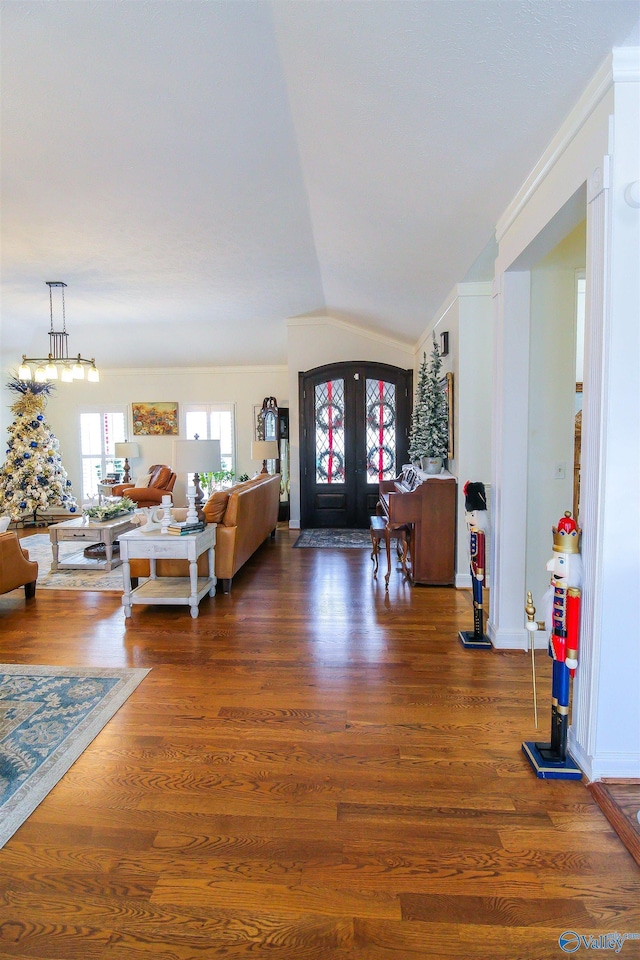 living room with french doors, dark wood-type flooring, vaulted ceiling, and ornamental molding