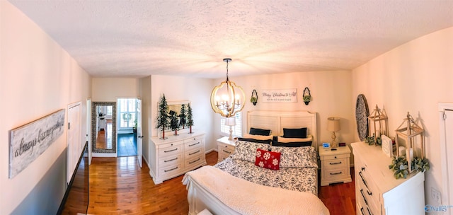 bedroom with a textured ceiling, dark hardwood / wood-style floors, and a notable chandelier