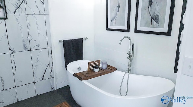 bathroom with tile walls and a tub