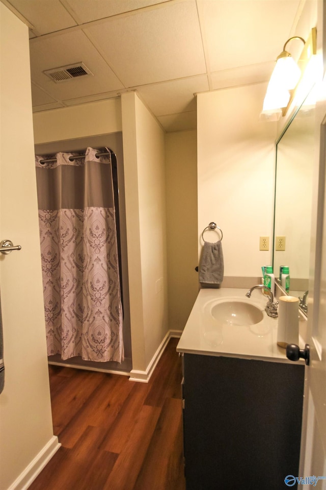 bathroom featuring wood-type flooring, vanity, a drop ceiling, and curtained shower