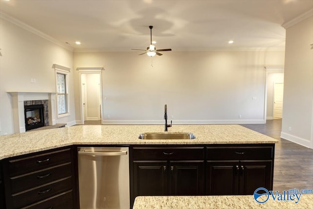 kitchen featuring sink, light stone counters, a fireplace, ornamental molding, and stainless steel dishwasher