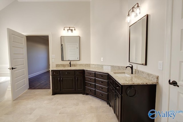 bathroom featuring vanity, lofted ceiling, tile patterned floors, and a tub to relax in