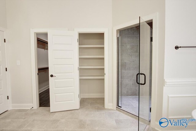 bathroom featuring tile patterned flooring, built in shelves, and walk in shower