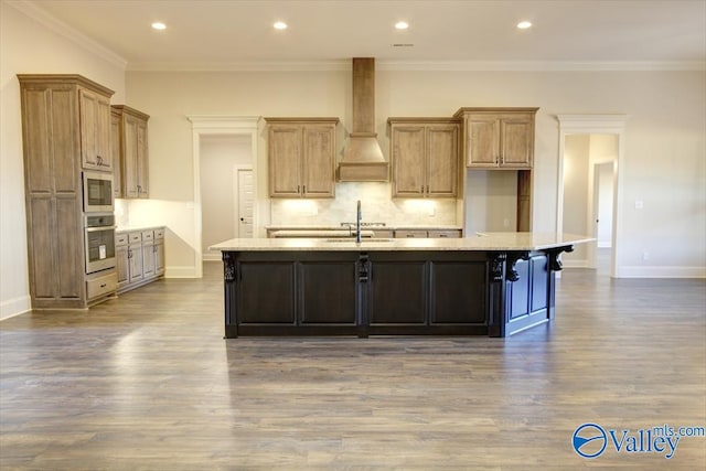 kitchen featuring premium range hood, built in microwave, a center island with sink, oven, and hardwood / wood-style floors