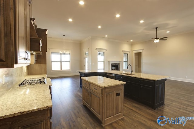 kitchen with sink, crown molding, a center island, light stone counters, and tasteful backsplash