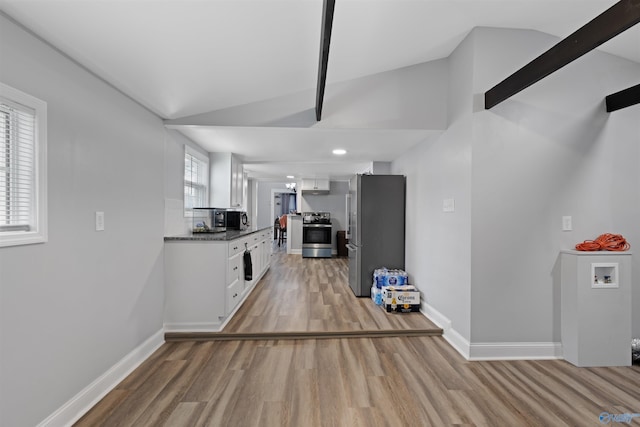 kitchen featuring stainless steel appliances, lofted ceiling, and white cabinets