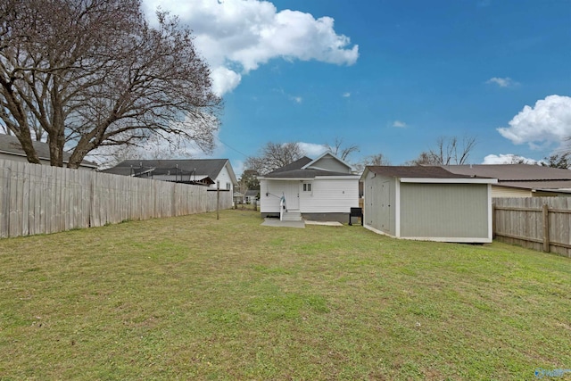 view of yard featuring an outbuilding, a fenced backyard, and a storage unit