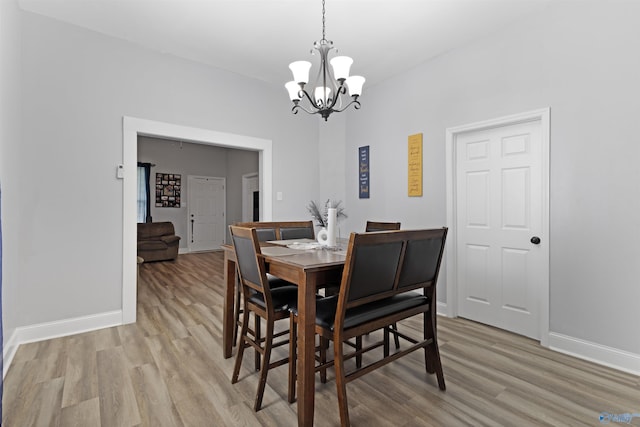 dining area featuring a chandelier, baseboards, and light wood finished floors